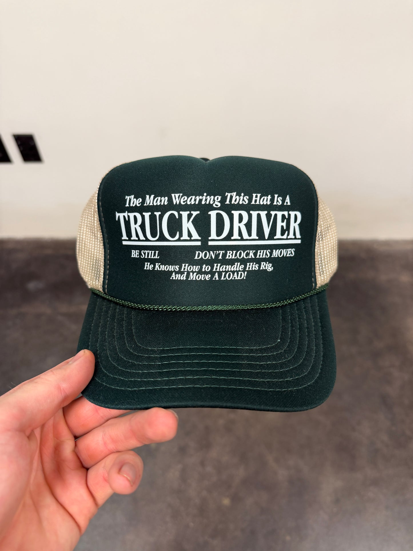 THE MAN WEARING THE HAT IS A TRUCK DRIVER